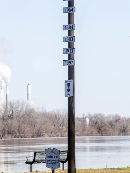 Flood gauge pole at Veterans Park in West Point, Kentucky, showing historic high-water marks from major floods.